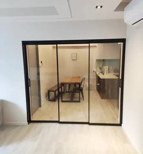 Black-framed synchronized sliding door with three clear glass panels, closed in front of a dining area