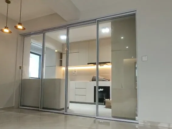 A silver-framed synchronized sliding door closed across a kitchen, which shows through the glass