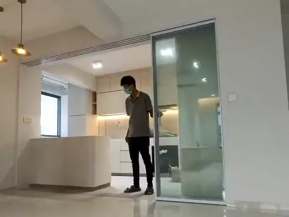 Video: a silver-framed synchronized sliding door closes off a kitchen as one panel is pulled, then opens again